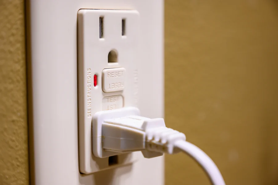 Close-up of a GFCI electrical outlet with reset and test buttons in a Wilson, NC home.