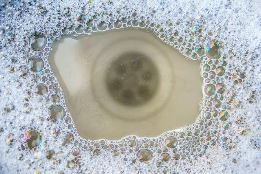 Close-up of a clogged drain with standing water and soap buildup in a Wilson, NC home.