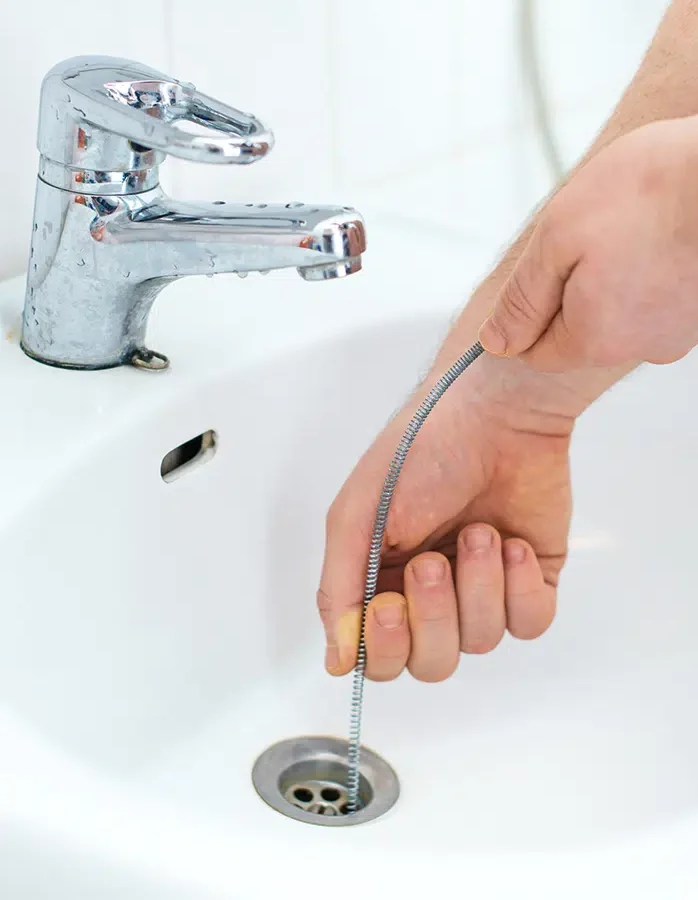 Prostar plumber using a drain snake to clear a clogged bathroom sink drain in Wilson, NC.