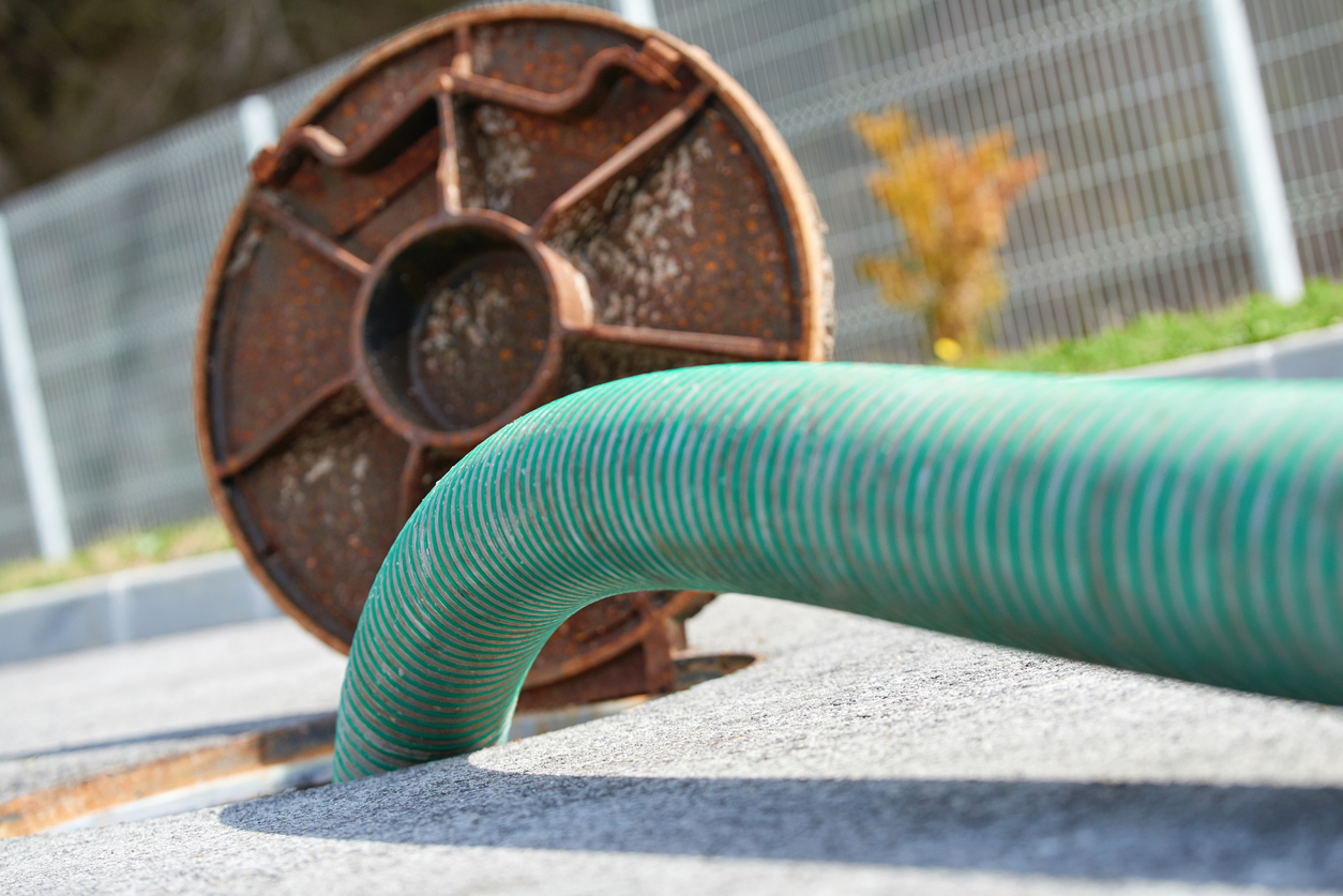 Green hose inserted into outdoor sewer line in Wilson, NC, illustrating professional drain cleaning and sewer line maintenance service