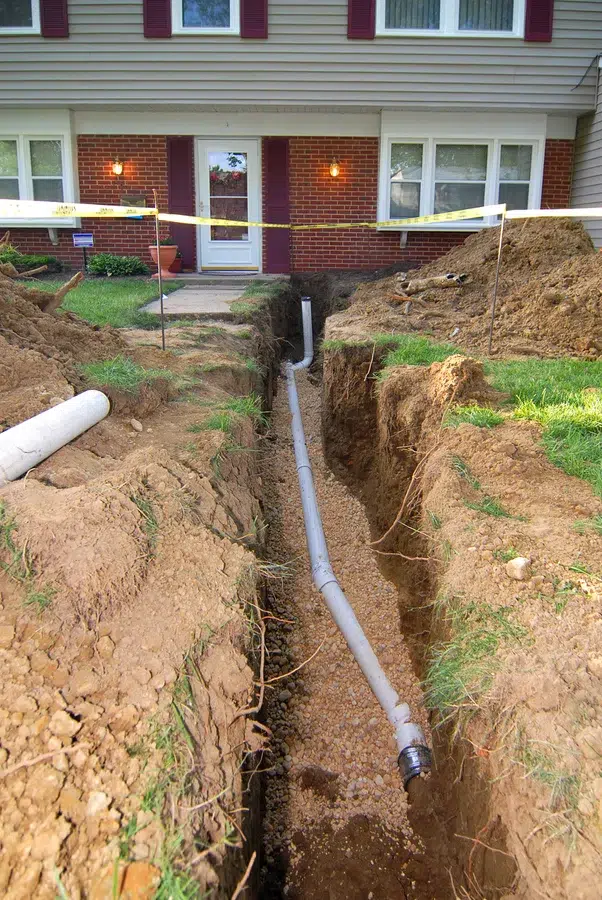 Sewer line installation trench with new piping running from a residential home in Wilson, NC.