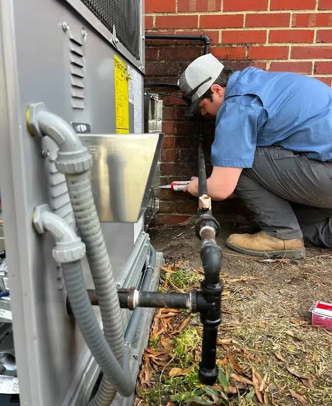 Technician sealing refrigerant lines on an outdoor HVAC unit during installation in Wilson, NC.