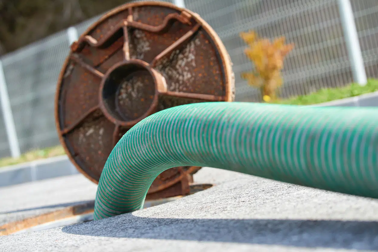 Green hose inserted into outdoor sewer line in Wilson, NC, illustrating professional drain cleaning and sewer line maintenance service