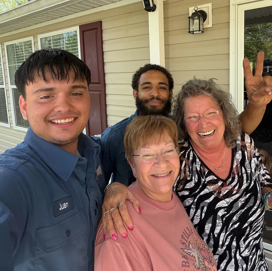 Smiling Prostar Services technicians with happy homeowners after HVAC service visit in Wilson County outside a residential home